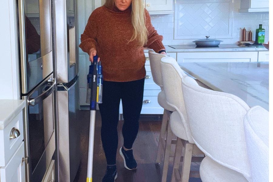 Woman vacuuming wooden kitchen floor