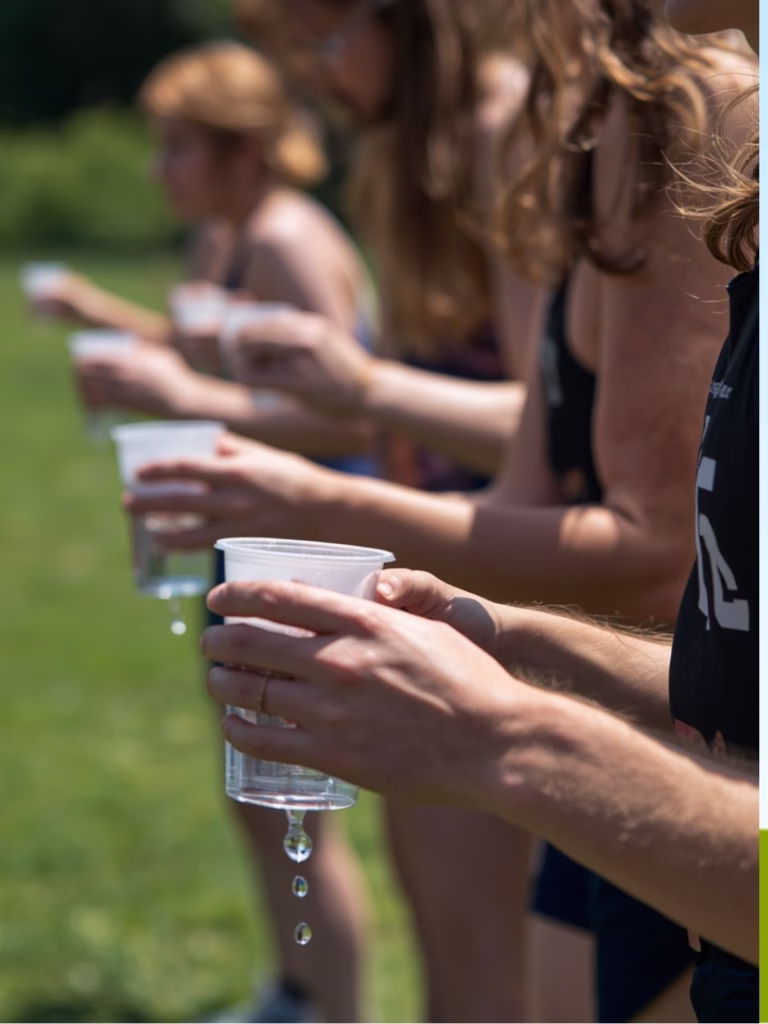 a line of people holding dripping cups of water