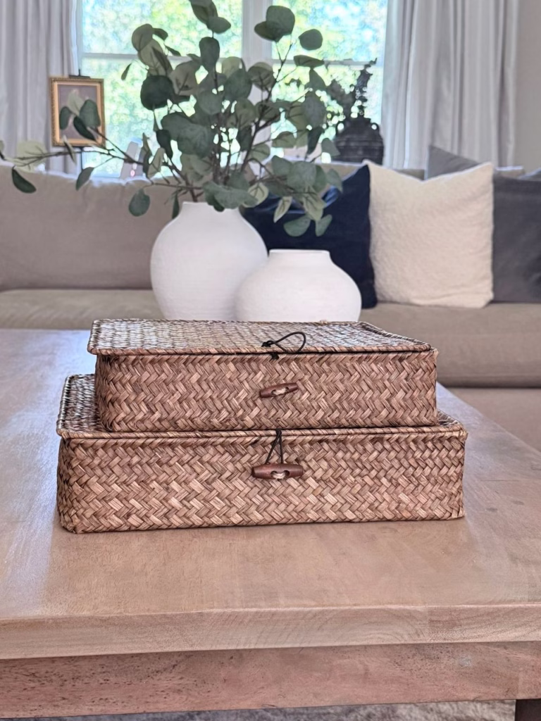 two wicker boxes with two white vases behind it.