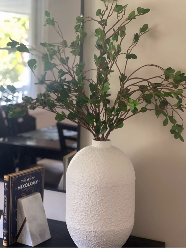 a white vase with green twigs coming out of it and two books in between bookends
