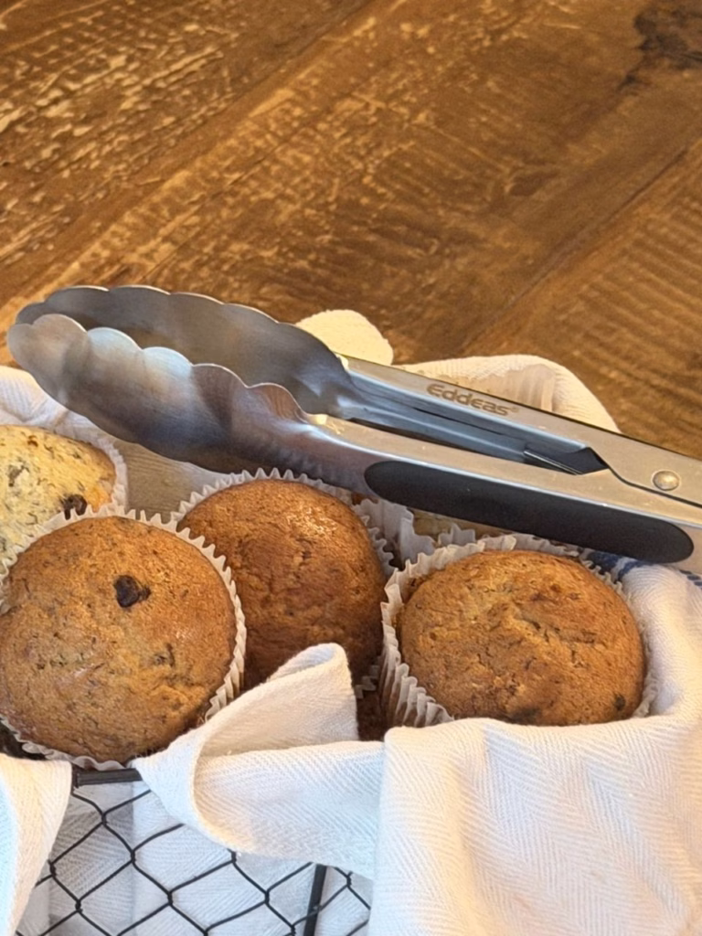 muffins in a basket with tongs resting on it.